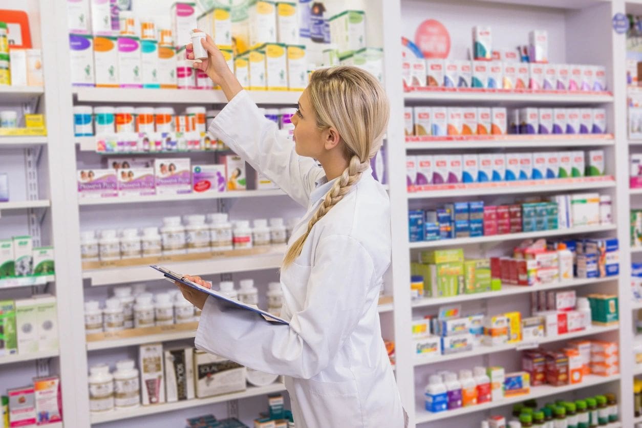 A woman in white lab coat holding a tablet.