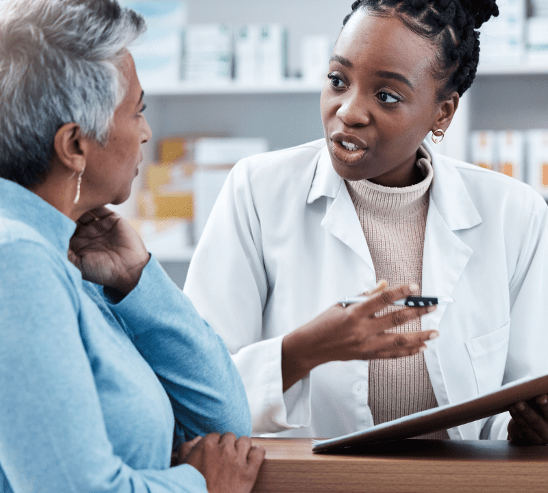 A woman talking to an older person in front of a table.